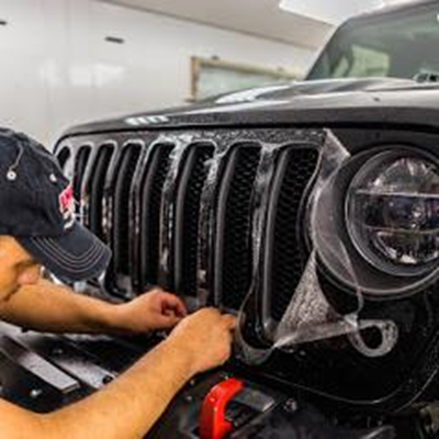 Man applying auto film to car Jeep grille